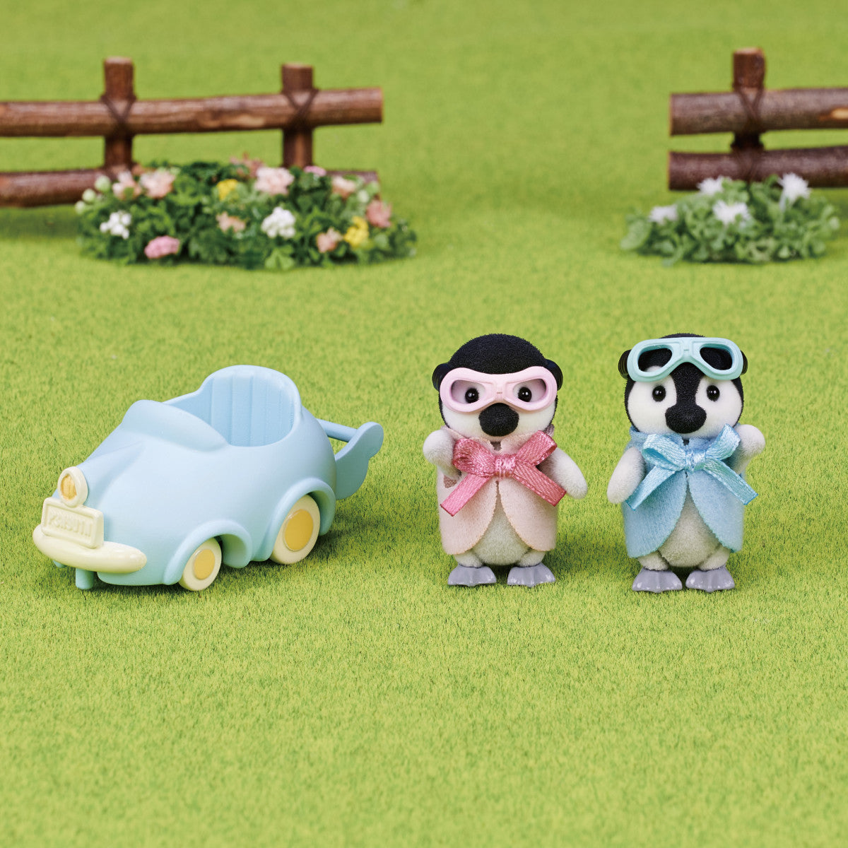 Penguin Babies Ride with twin figures Pearl and Rocky in pastel outfits and a light blue pushcart on green grass background