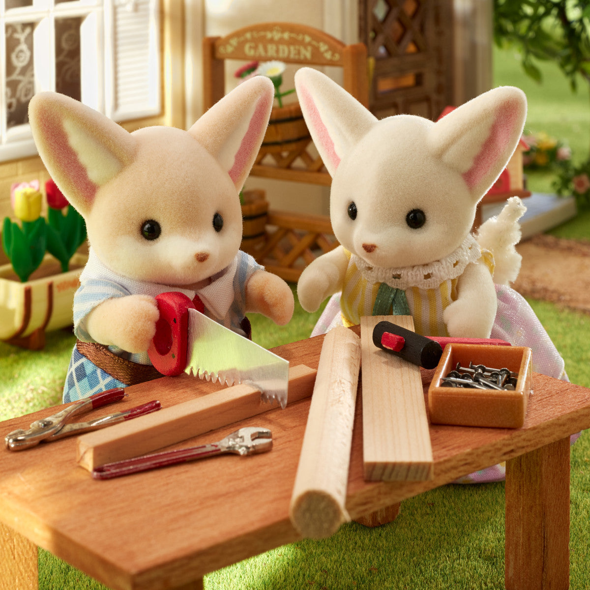 Fennec Fox Family figurines Ronald and Sharon crafting wood with detailed tools in a sunny garden scene.