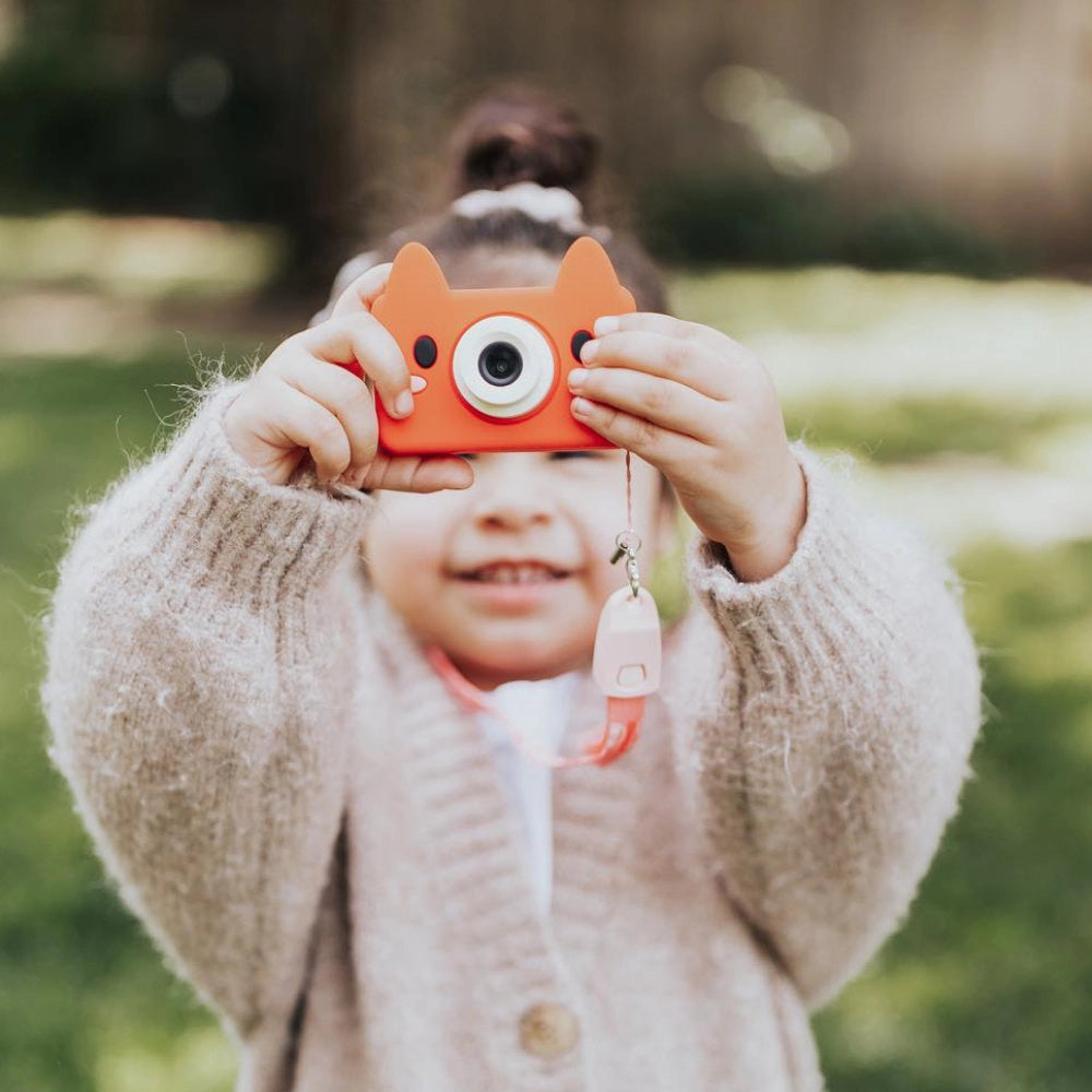 Child holding an orange Digital Camera Model C | Akito the Fox designed for kids aged 3 to 7 outdoors.