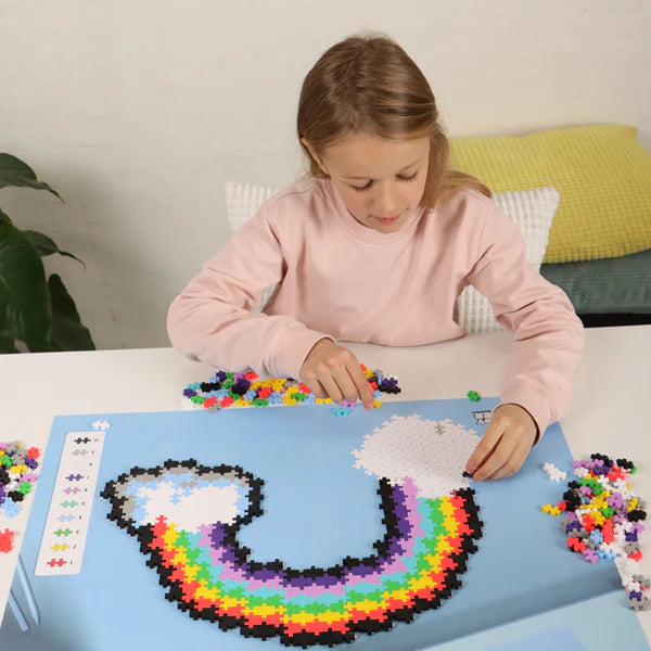 Child assembling colorful puzzle pieces on board with rainbow pattern in Plus Plus Puzzle by Number | Rainbow set