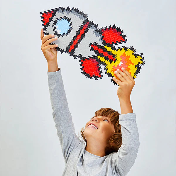 Child holding completed Plus Plus Puzzle by Number Rocket, colorful pixel-style rocket design made from interlocking pieces.