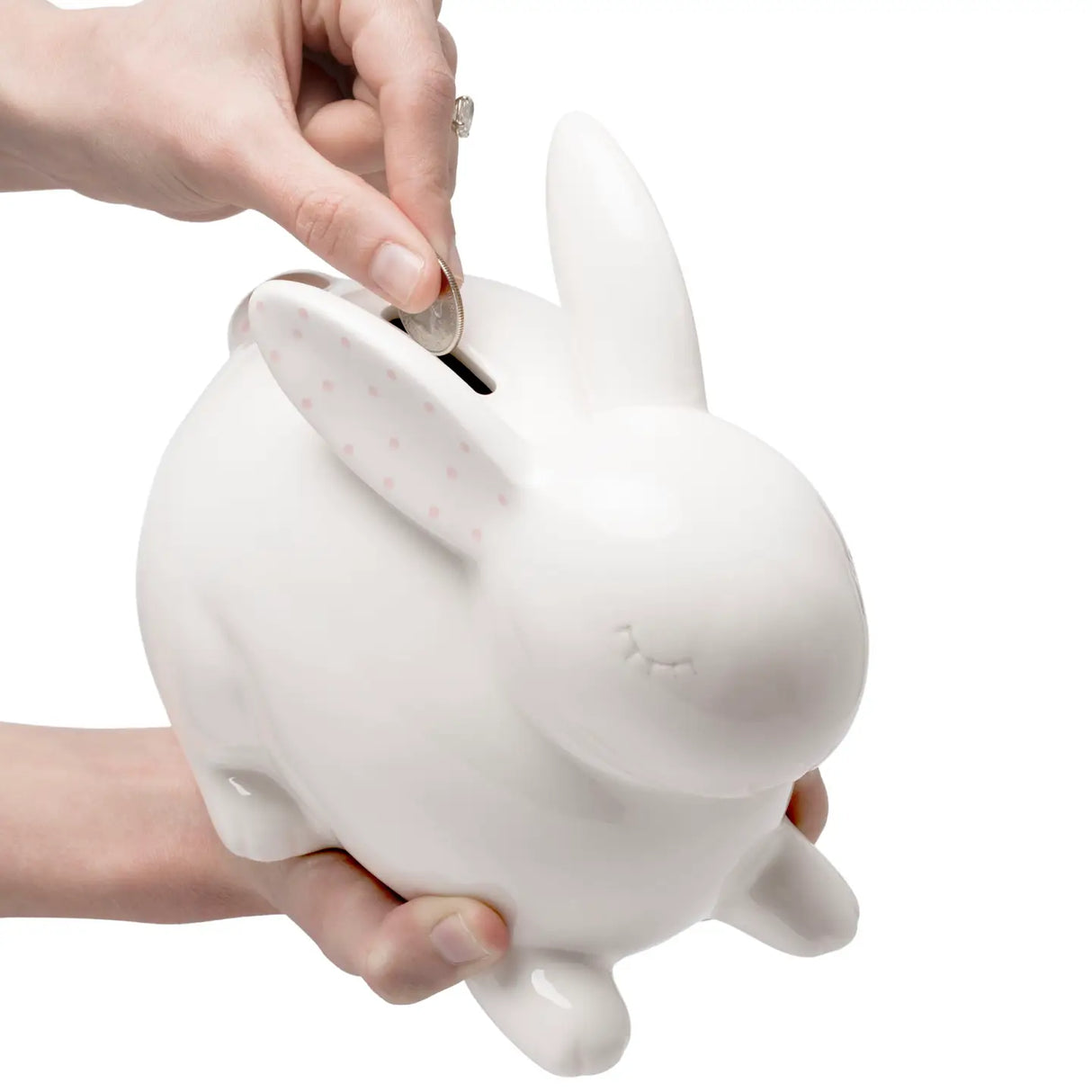 Ceramic Bunny Money Bank being held, showing a hand inserting a coin into the white ceramic bunny-shaped bank.