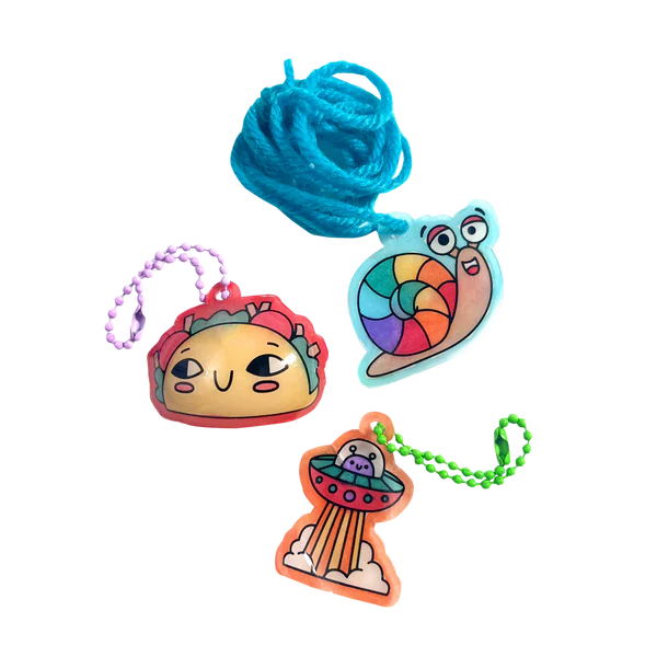 Shrink-Its! Fun Friends showing colorful shrink plastic charms of taco, snail, and UFO with attached ball chains.