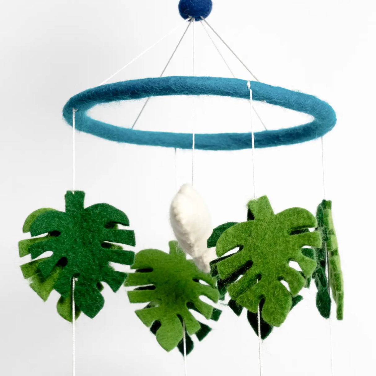 Felt Mobile | Baby Dinosaur featuring handmade felt green leaves and white dinosaur hanging from a blue felt hoop for nursery decor.