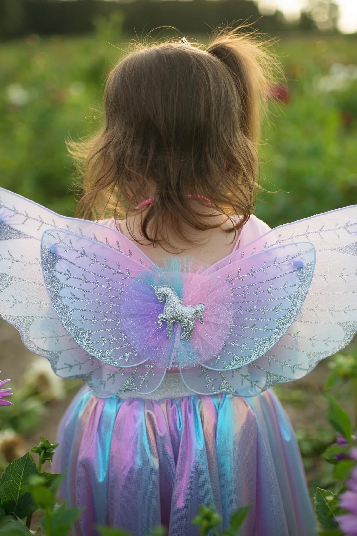 Child wearing Magical Unicorn Skirt & Wings with shiny iridescent skirt and bluish purple glittered tulle wings.