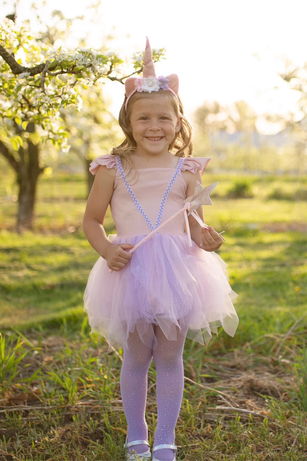 Pink Shimmer Unicorn Dress & Headband size 5-6 worn by smiling girl outdoors with wand and floral unicorn headband.
