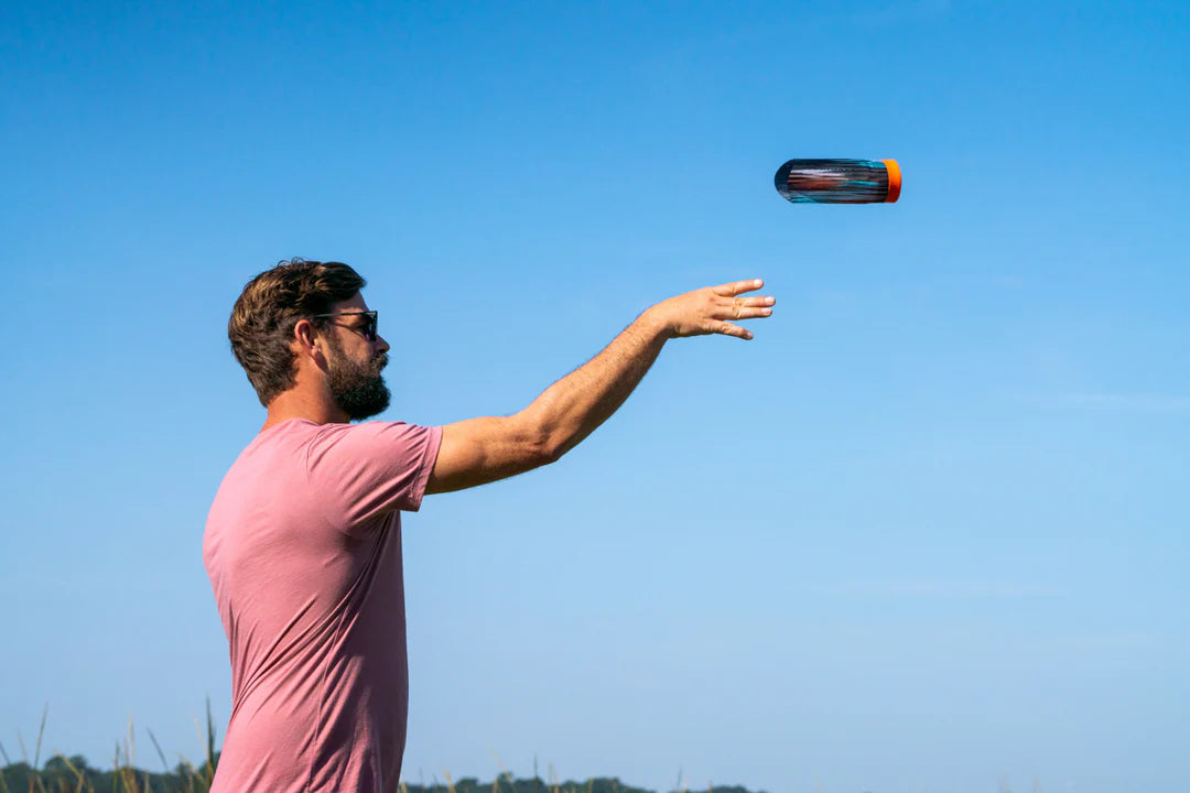 Man wearing sunglasses throwing Waboba Airlyft glider outdoors against clear blue sky