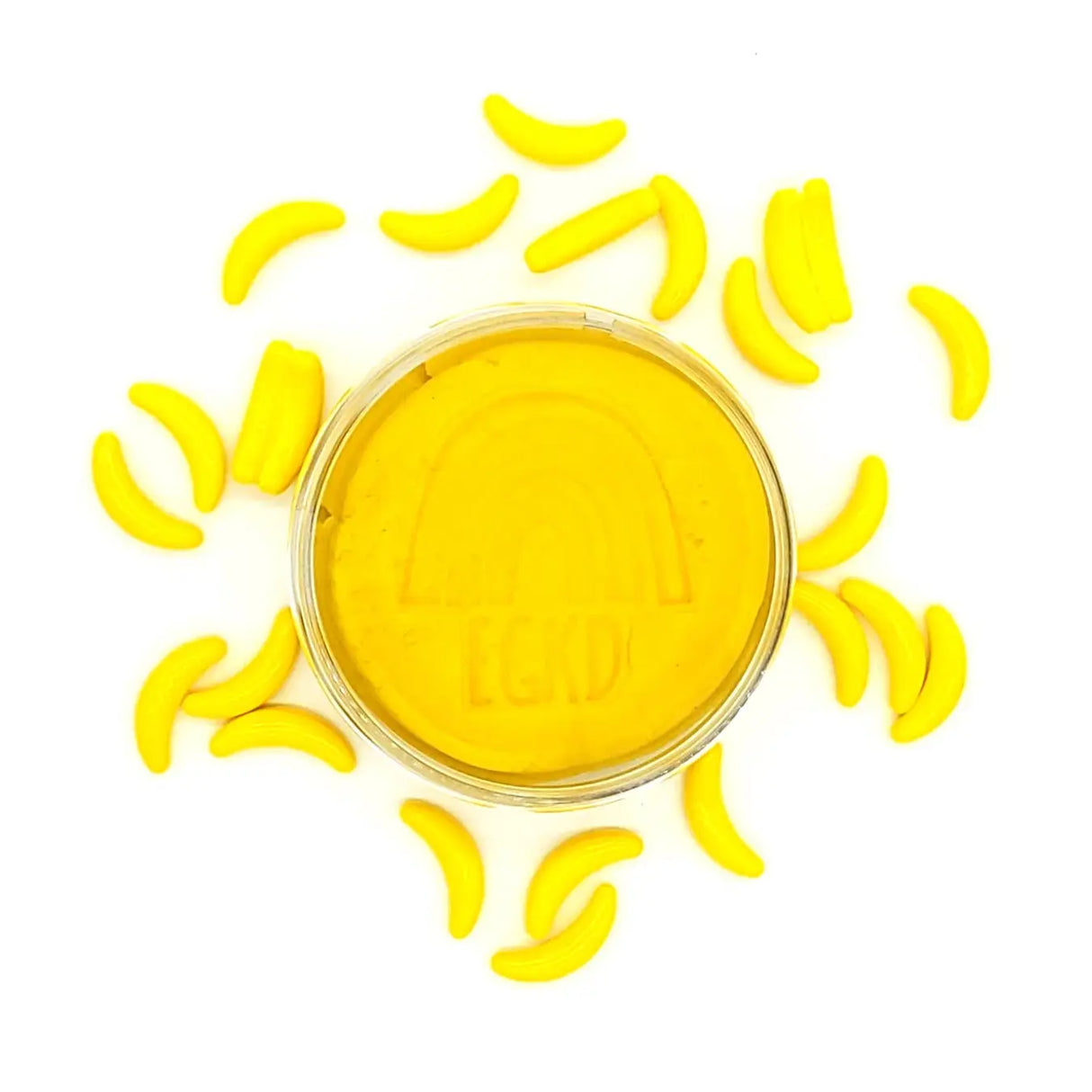 KidDough Glitter | Yellow in a container surrounded by small yellow banana-shaped dough pieces on a white background.