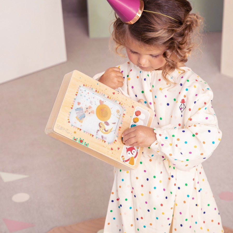 Young child playing with My First Animated Music Box featuring colorful illustrations and a handle for easy carrying.
