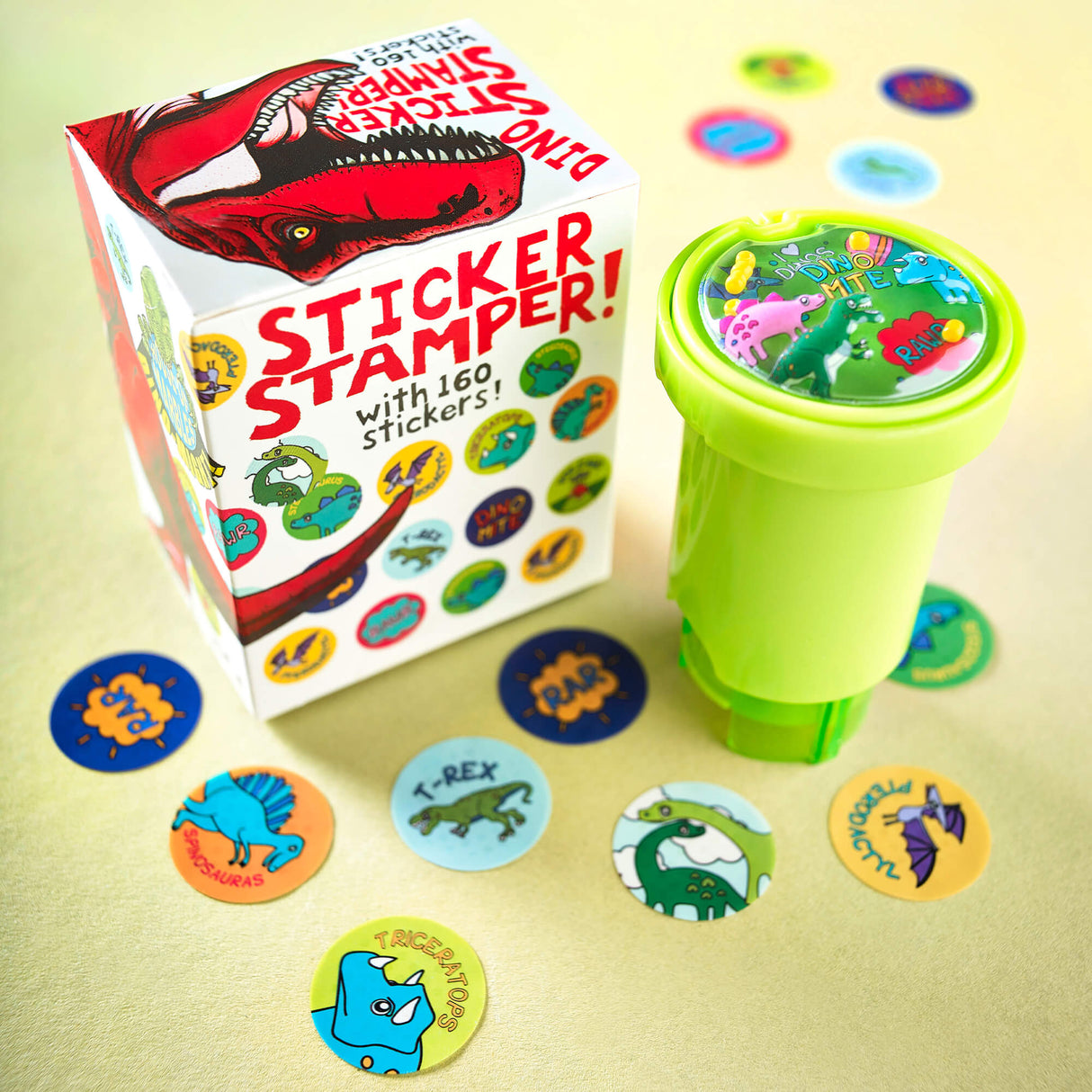 Depiction of Dinosaur Sticker Stamper next to box. Different stickers from the stamper are seen stamped below. For ages 3 and up.