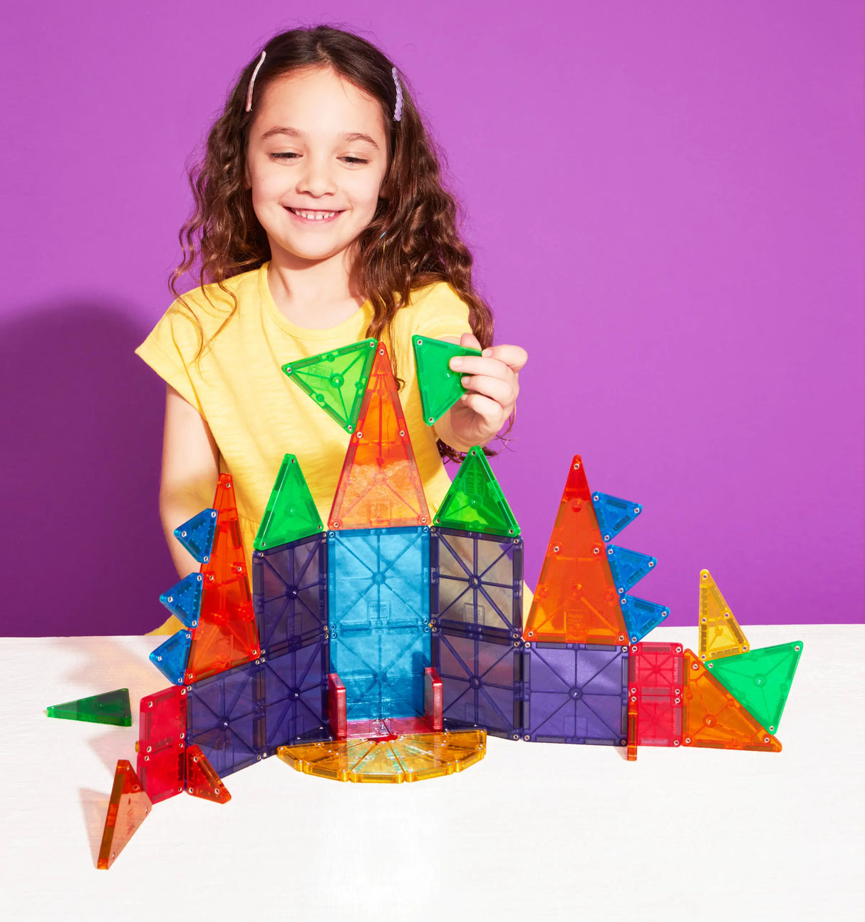 Child playing with colorful geometric shapes building a structure using Magnatiles Micromags Combo 46pc set