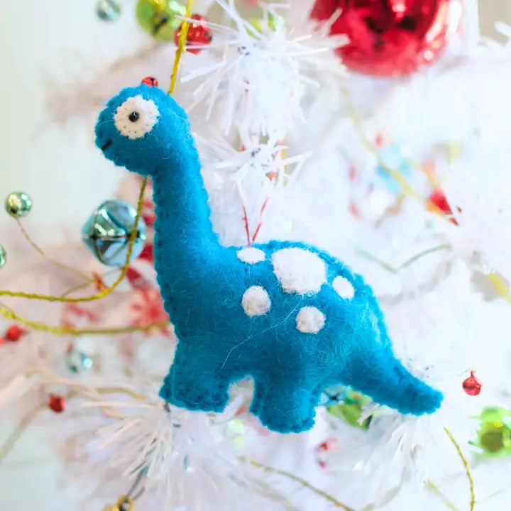 Brachiosaurus Dino Felt Ornament in blue and white sheep wool hanging on a decorated Christmas tree branch.