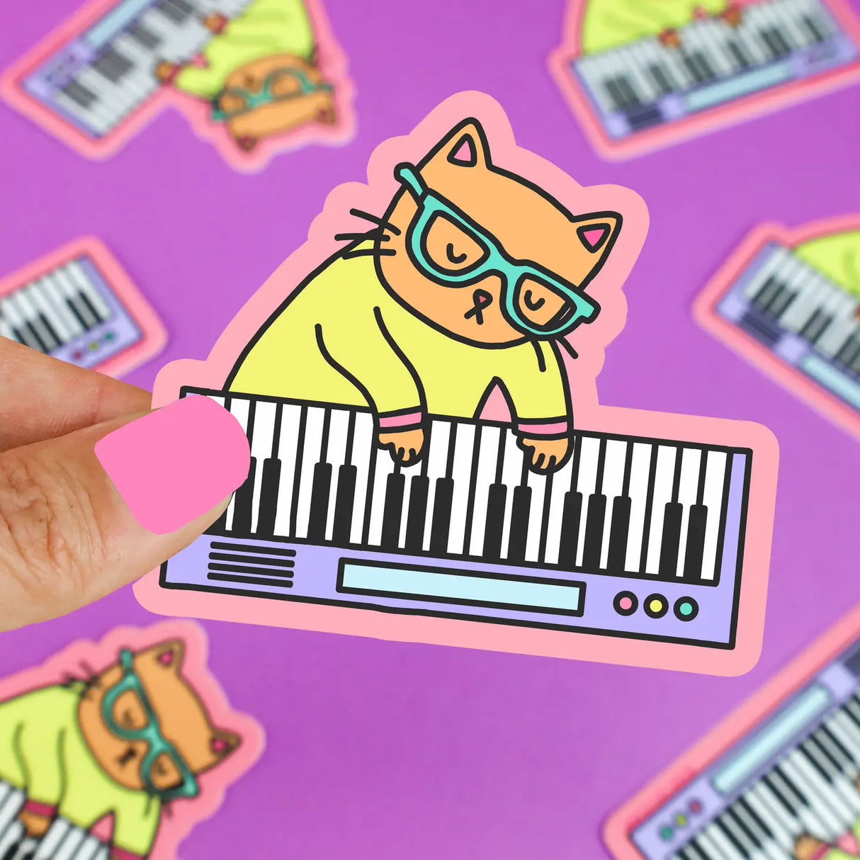 Keyboard Cat Sticker showing a cat wearing glasses playing a keyboard, printed on durable vinyl with a pink border.