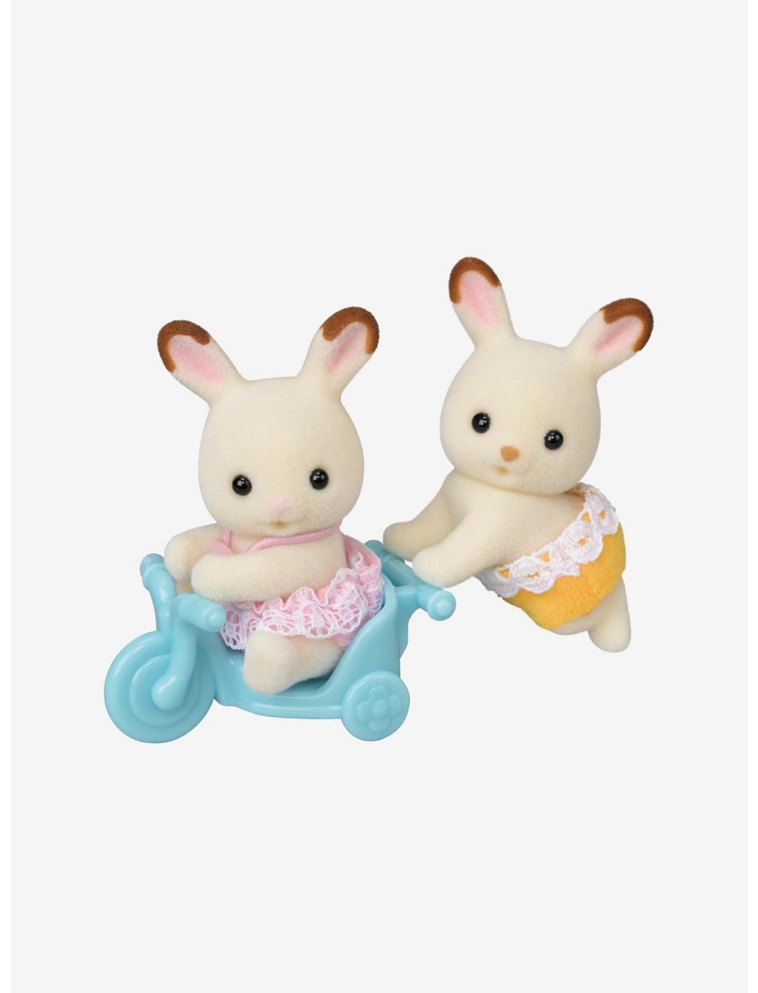 Chocolate Rabbit Twins bunny figures with one riding in a blue toy cart and one standing beside it