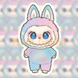 Cute pastel rainbow character with big sparkly eyes and bunny ears in a soft vinyl sticker design
