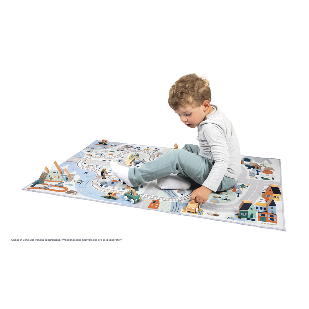 Child playing on the Crossroads White Valley Play Mat featuring snowy mountain roads and a railroad track.
