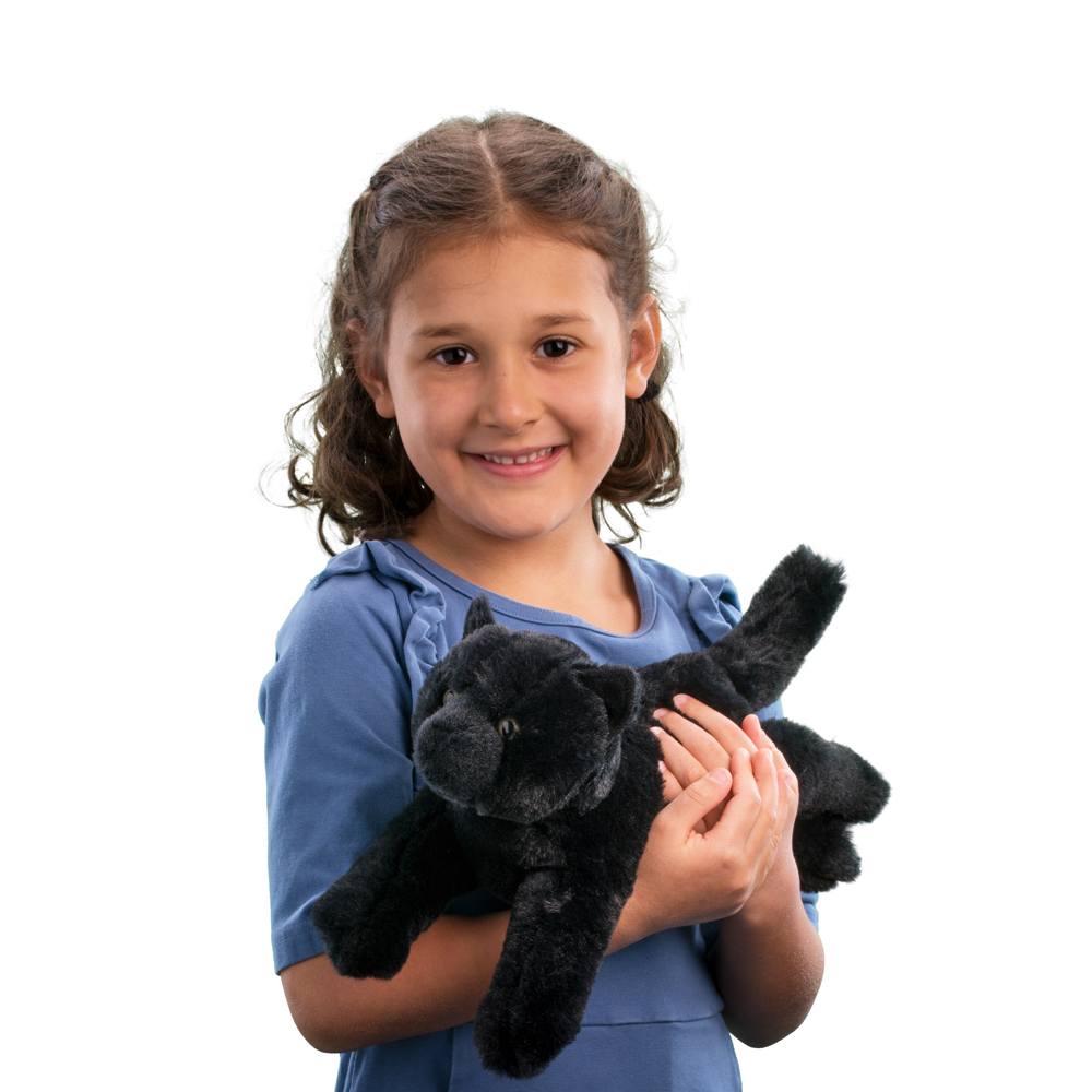 Young girl smiling and holding plush Black Cat Tug stuffed animal with soft black fur and green eyes.