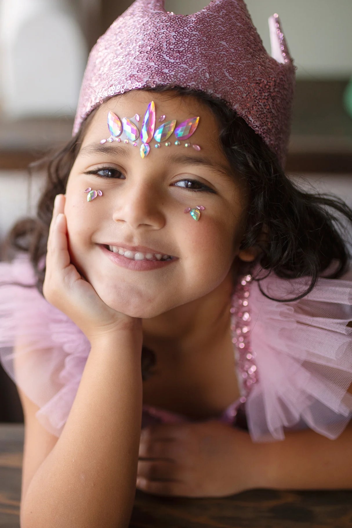 Smiling child wearing the Gracious Pink Sequins Crown with soft pink satin lining and decorative face jewels.