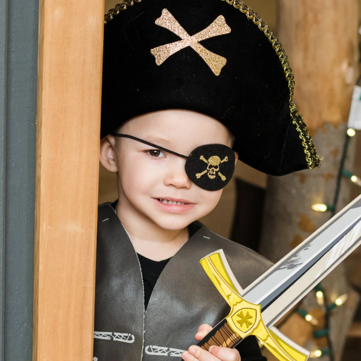 Child dressed as pirate wearing a Pirate Eye Patch and hat holding a toy sword for imaginative play.