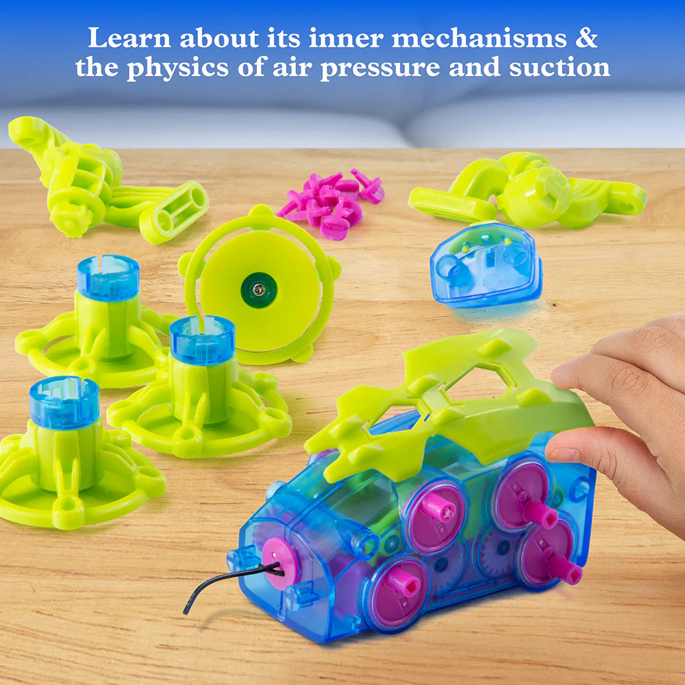 Hand assembling colorful robotic gecko parts demonstrating suction cup and air pressure mechanisms on wooden table