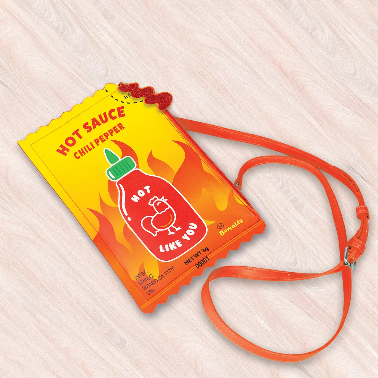Crossbody Handbag | Hot Sauce shaped like a playful hot sauce packet with bright orange strap and flame design.