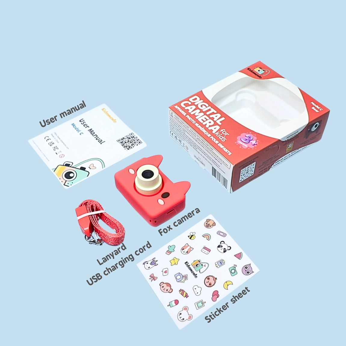 Digital Camera Model C | Akito the Fox with fox-shaped camera, user manual, lanyard, USB cord, and sticker sheet on light blue background.
