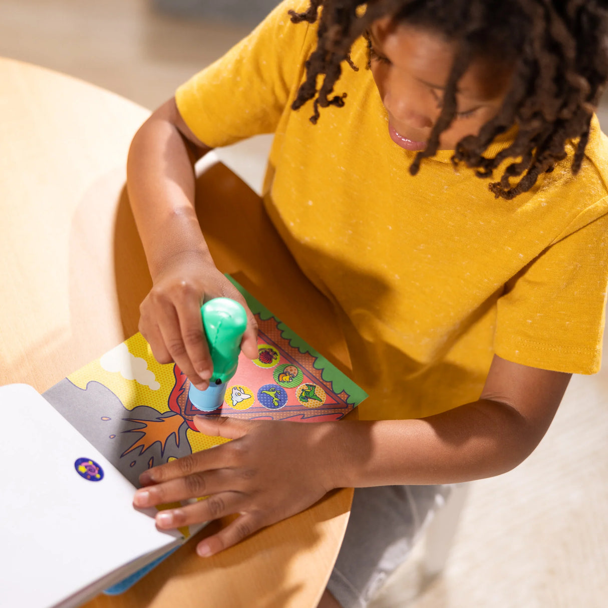 Child using Sticker WOW! Dino stamper on activity book with colorful prehistoric-themed stickers and pages.