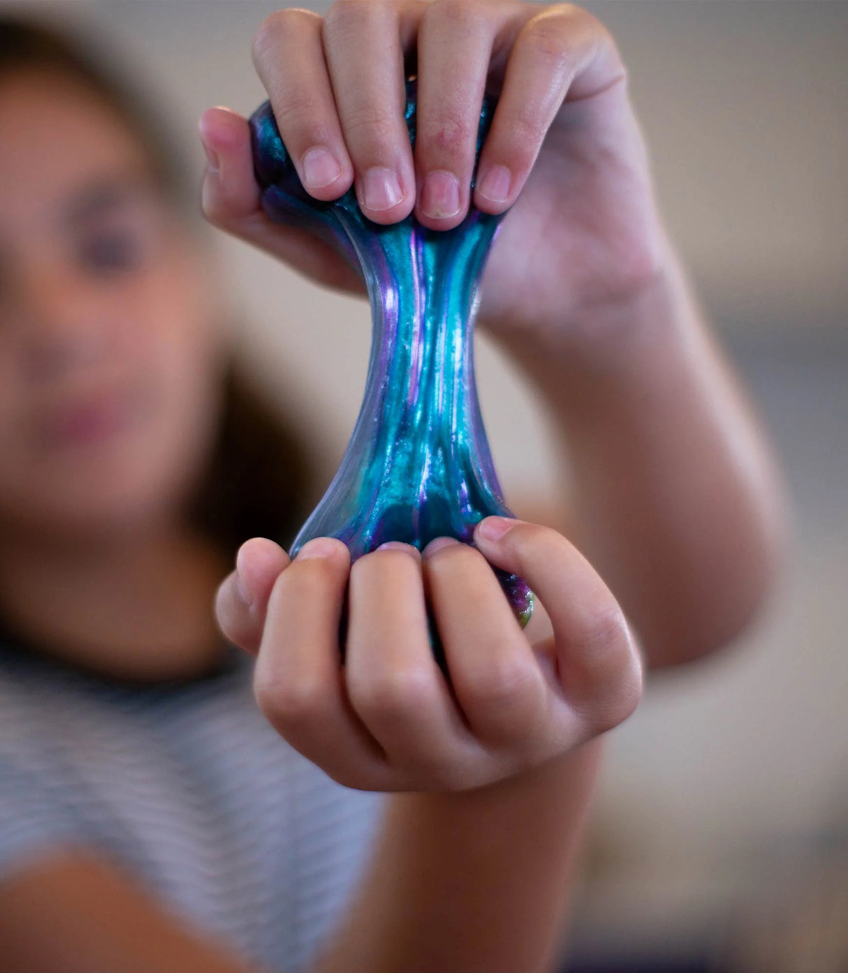 Child stretching colorful, purple and blue Super Illusions Super Scarab Thinking Putty with soft texture and color-shifting effect.