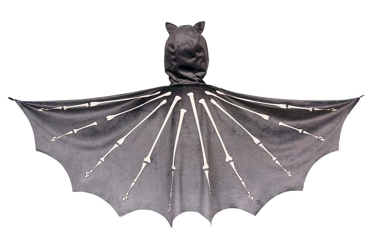 Child wearing a grey velvet bat cape with printed bat skeleton wings and attached hood with ears.