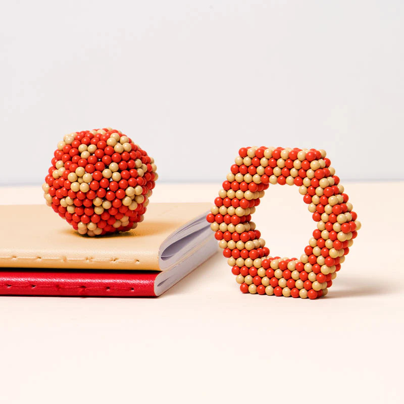 Speks Elements Solar magnetic balls shaped into a sphere and hexagon on a desk for creative building.