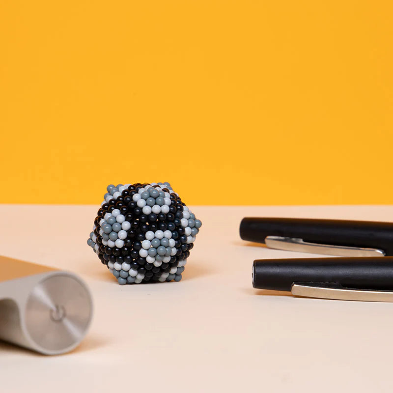 Speks. Pixel. Game Over. magnetic balls shaped into a black and white pixelated design on desk with pens.