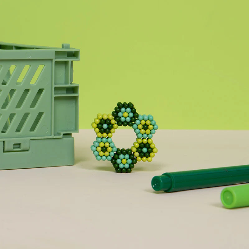Speks. Pixel. Motherboard. magnetic balls formed in a colorful hexagonal pattern next to green pens and crate.