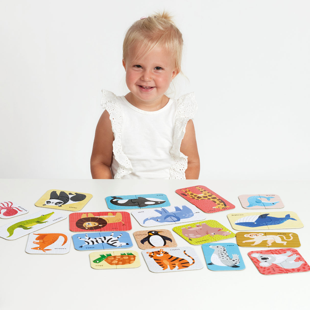 Toddler smiling with Puzzle Pairs Wild Animals two-piece puzzles featuring colorful wild animal illustrations.