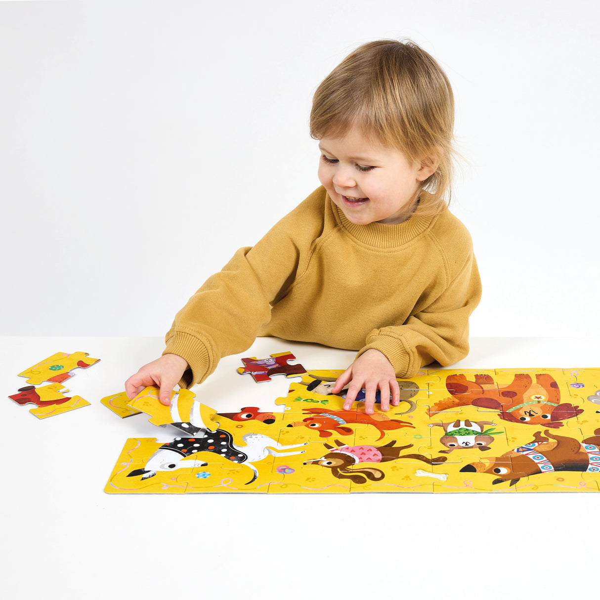 Child assembling the 40pc I Love Dogs Puzzle featuring colorful, playful dogs and puppies on a bright yellow background.