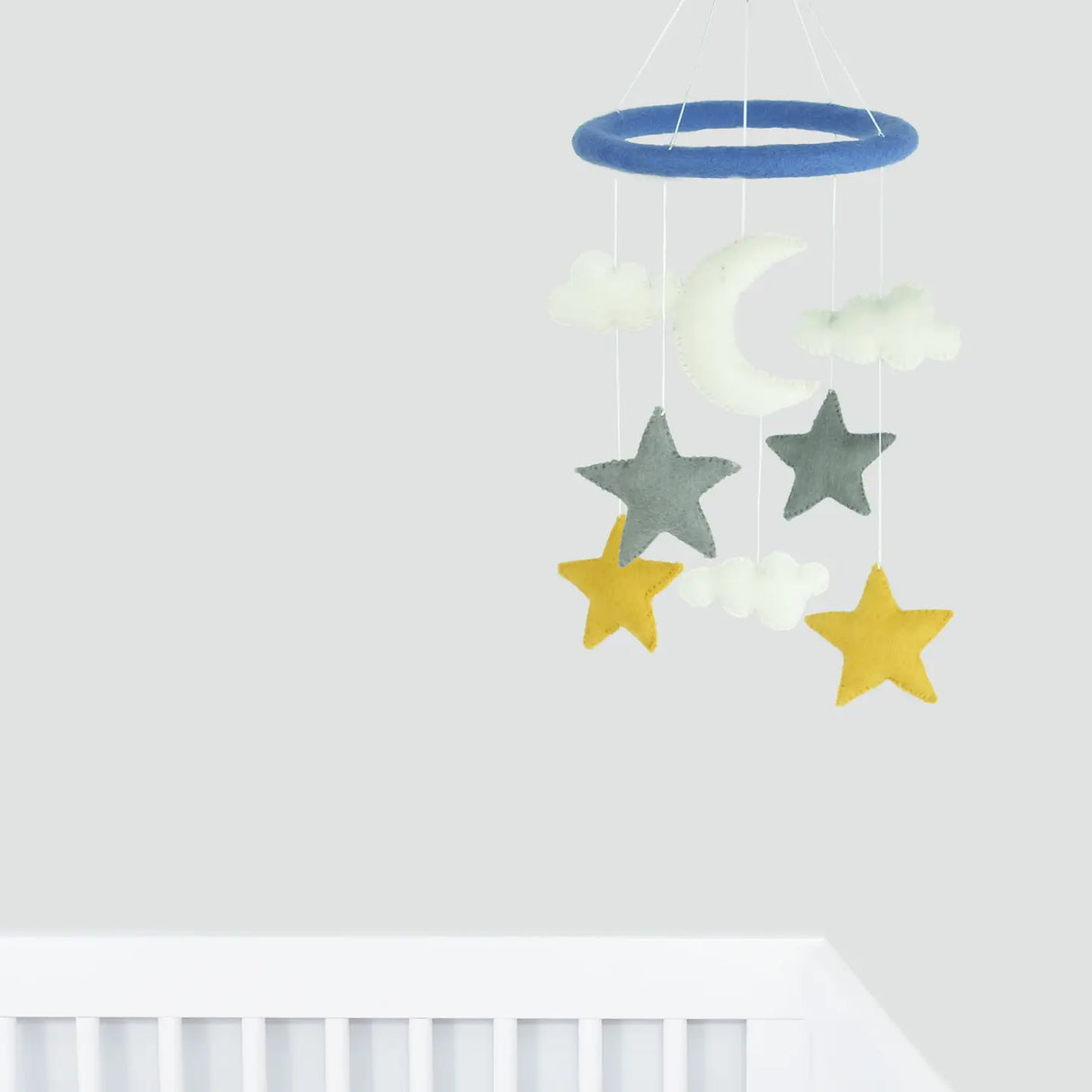 Felt Mobile | Stars and Moon hanging above white crib featuring felt stars, moon, and clouds in soft colors.