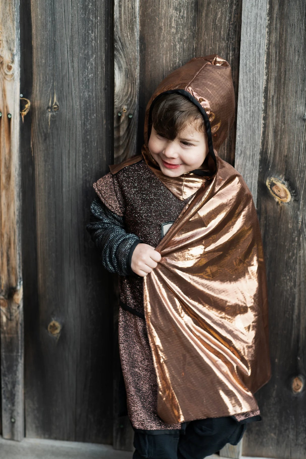 Child wearing Brilliant Copper Knight Tunic with Cape featuring a sparkly hooded tunic and shiny copper cape.
