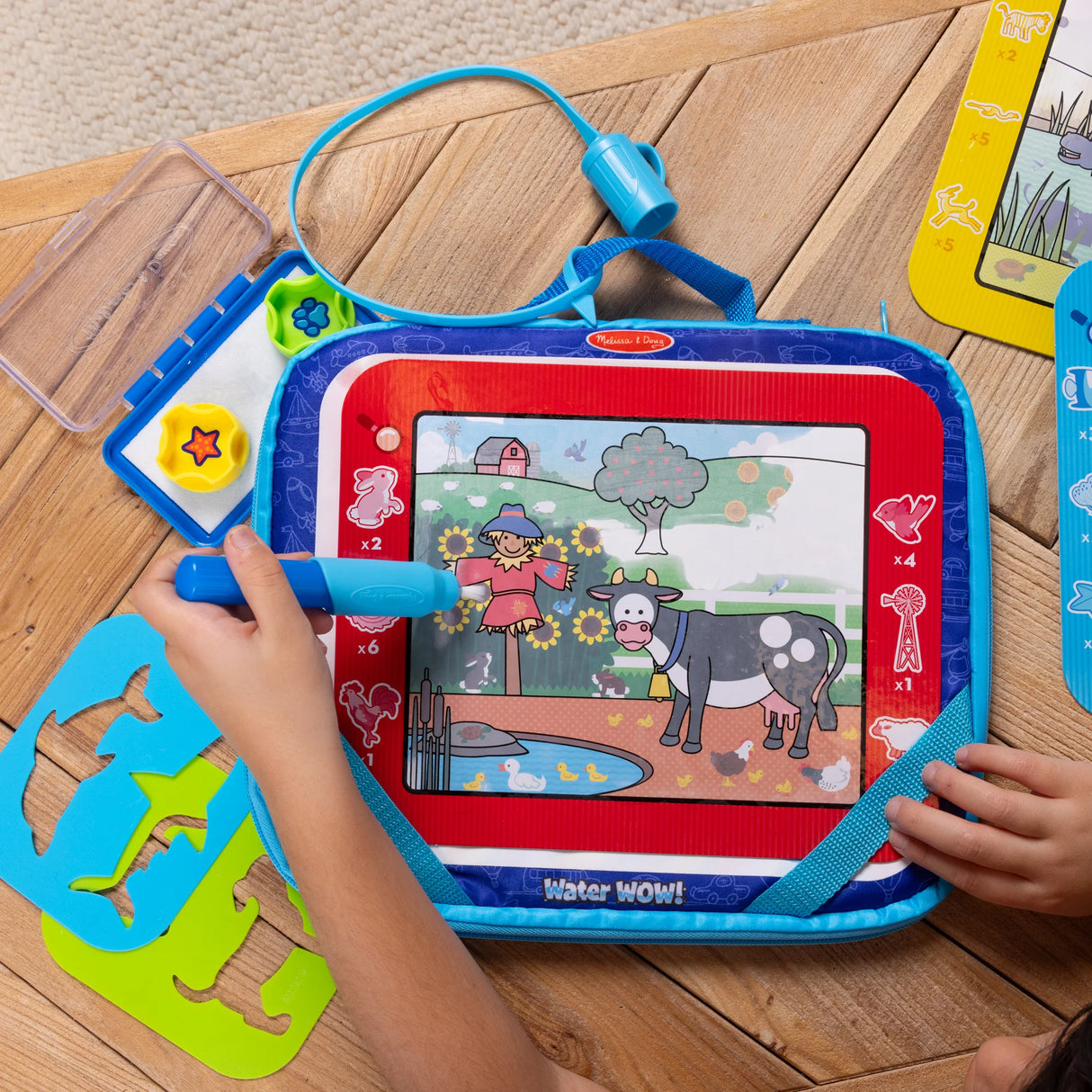 Child using a Water WOW! drawing set with water pen revealing colorful farm scene on built-in board