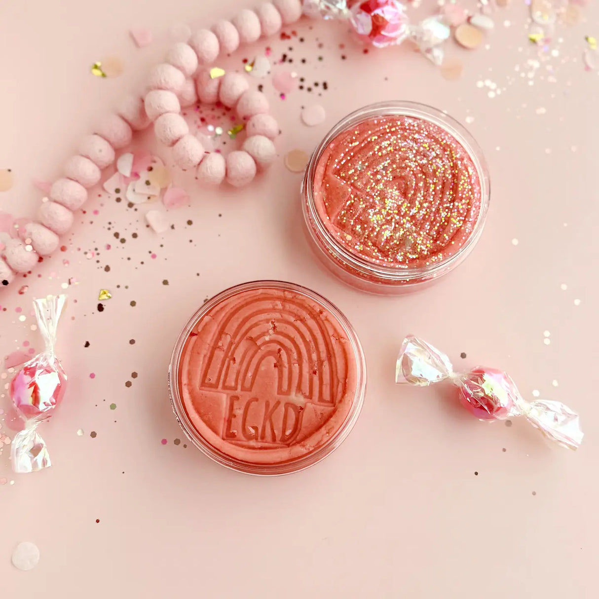 KidDough Glitter | Pink sensory dough with glitter in clear containers on a pink festive background.