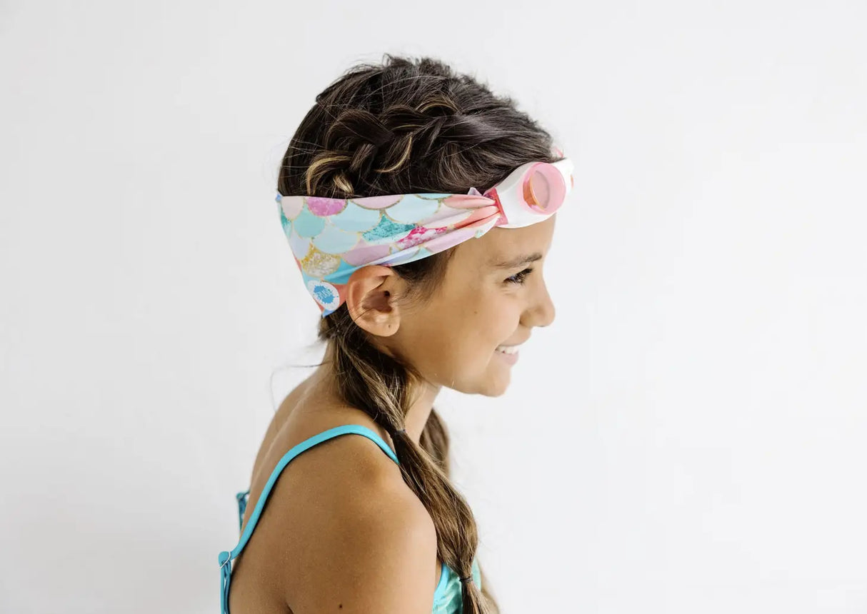 Young girl wearing Goggles Mermaid swim goggles with a colorful mermaid scale strap and white frame.