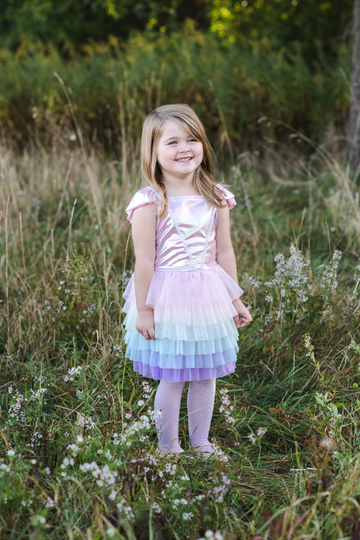 Little girl standing in a field wearing a pastel Rainbow Ruffle Tutu Dress Size 5-6 with layered tulle skirt and shiny top.