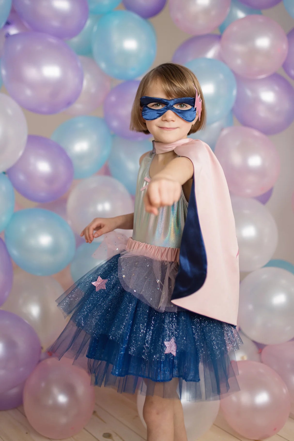 Child wearing the Super Duper Tutu, Cape & Mask set with glittery tutu, pink and navy cape, and matching mask.
