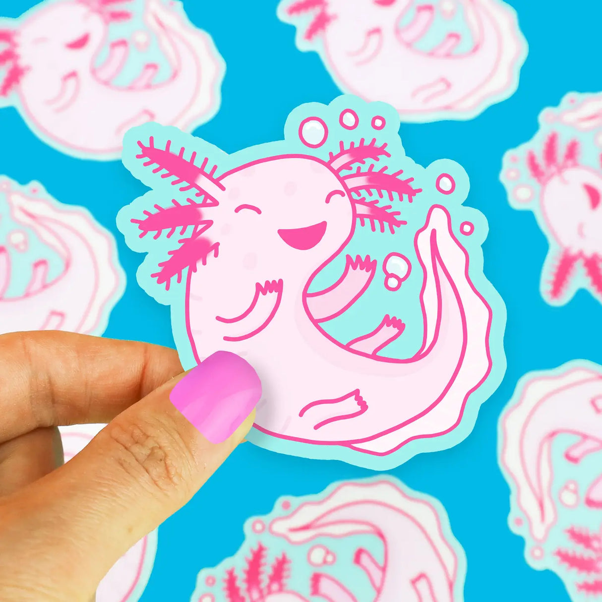 Pink Axolotl Sticker showing a smiling vinyl axolotl, waterproof and durable, held by a hand with pink nails.