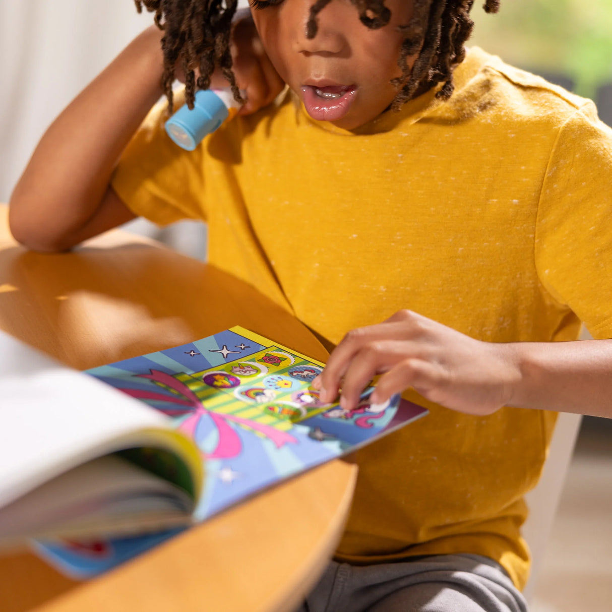 Child using Sticker WOW! Unicorn sticker stamper engaging with colorful activity book at table.