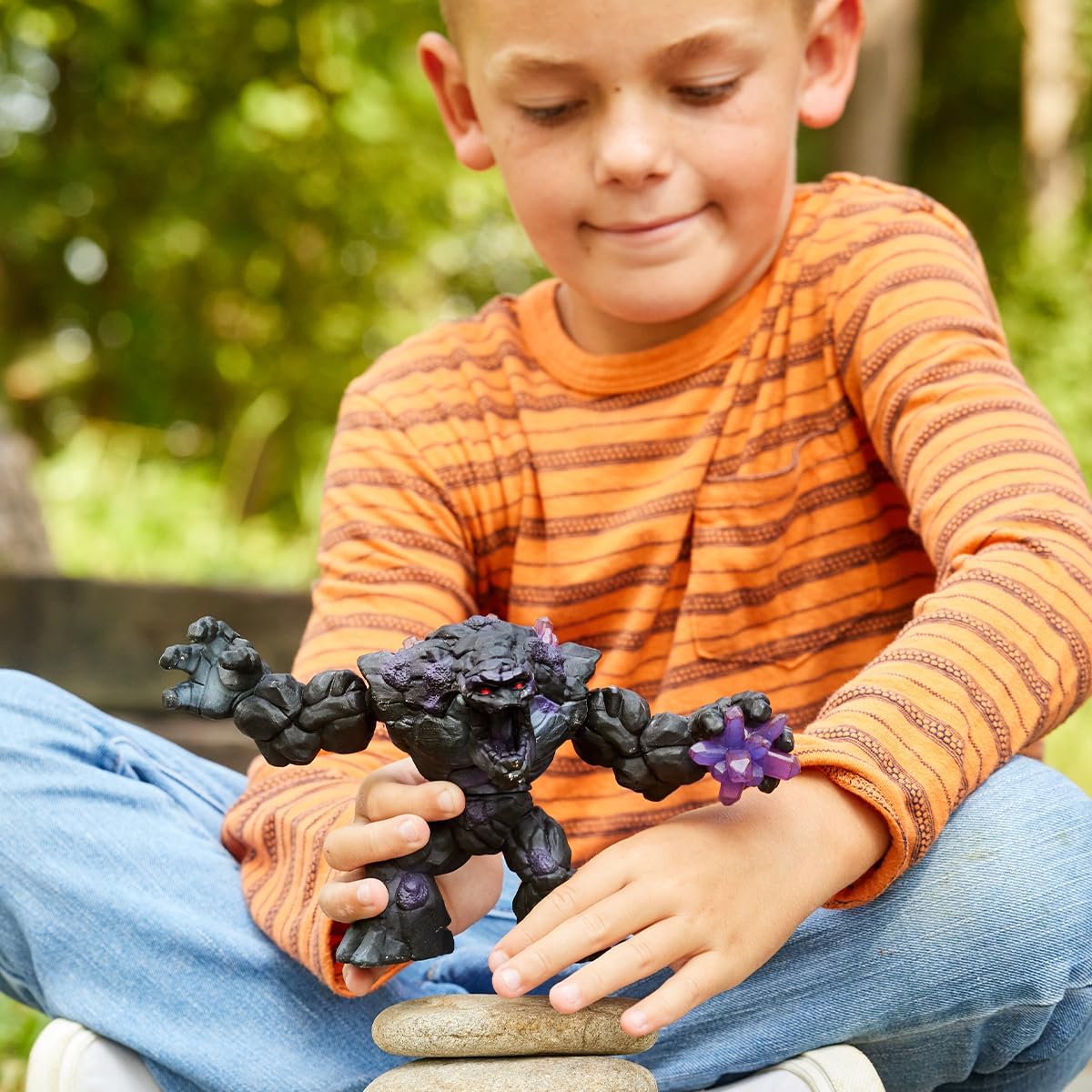 Child playing outdoors with Eldrador Creatures Shadow Stone Monster toy, a dark stone creature with crystal claws.