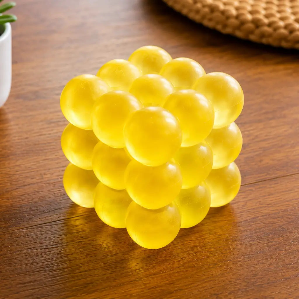 Feelzies Slow Flow Bubble Cube, yellow tactile bubble cube on a wooden table