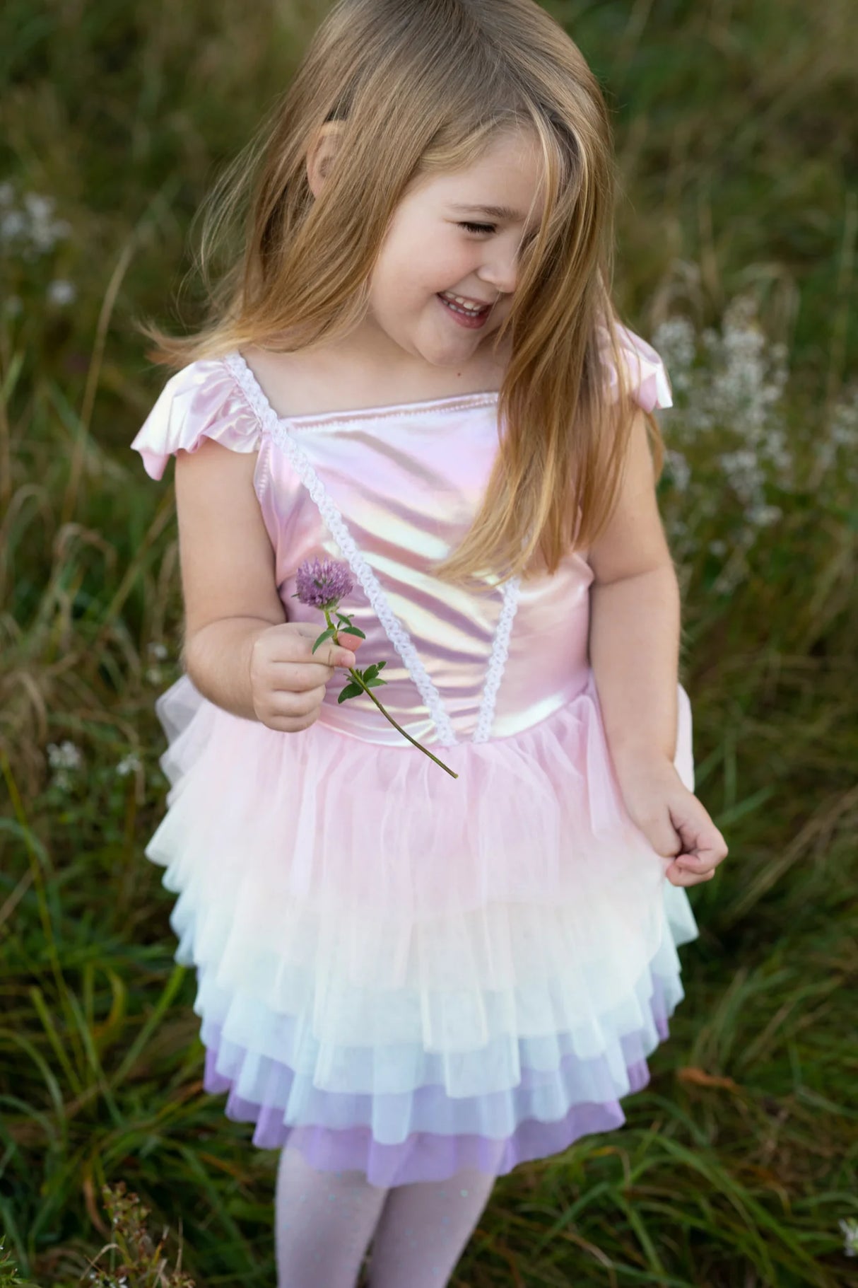 Young girl wearing Rainbow Ruffle Tutu Dress | Size 5-6 with layered pastel tulle skirt and satin top outdoors smiling.