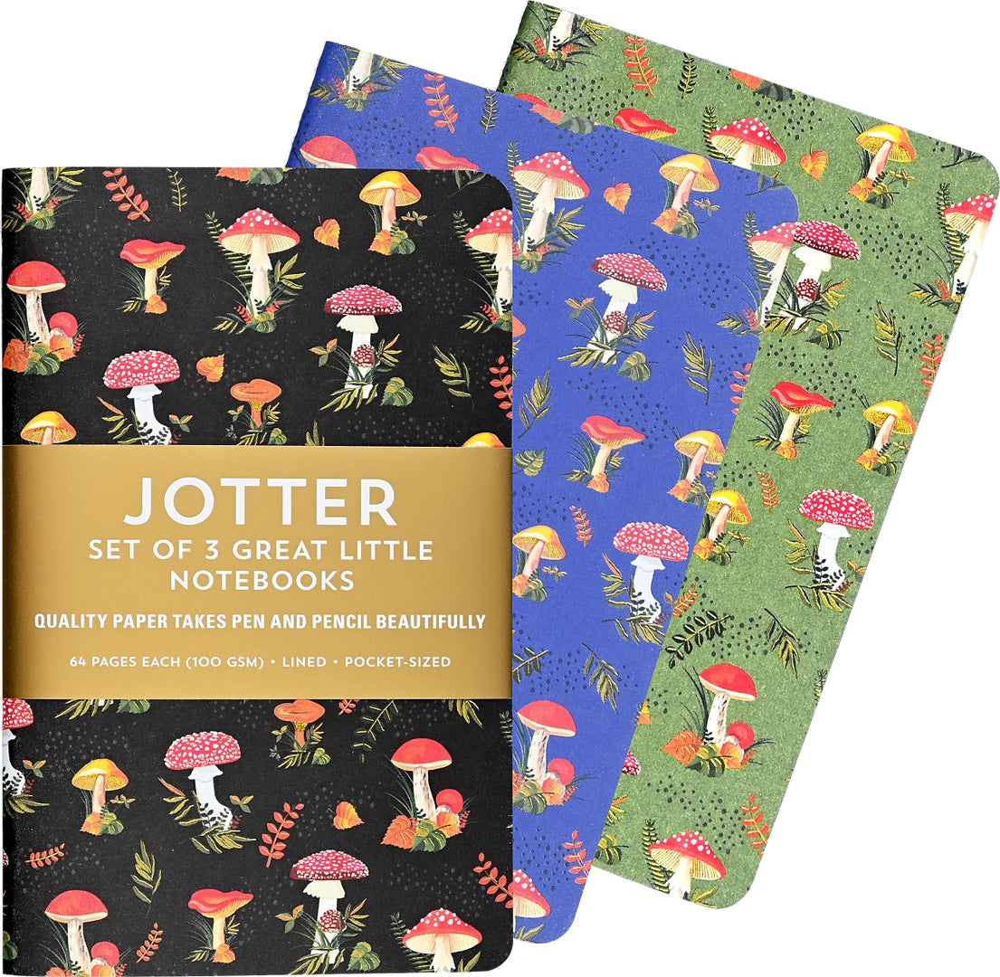 Set of three small notebooks with colorful mushroom and leaf designs on black, blue, and green covers with gold foil accents