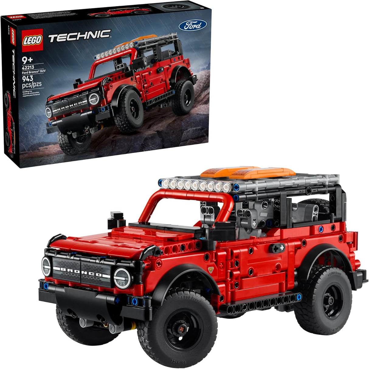 Red LEGO Technic Ford Bronco model with detailed features and box in background on rocky terrain display.