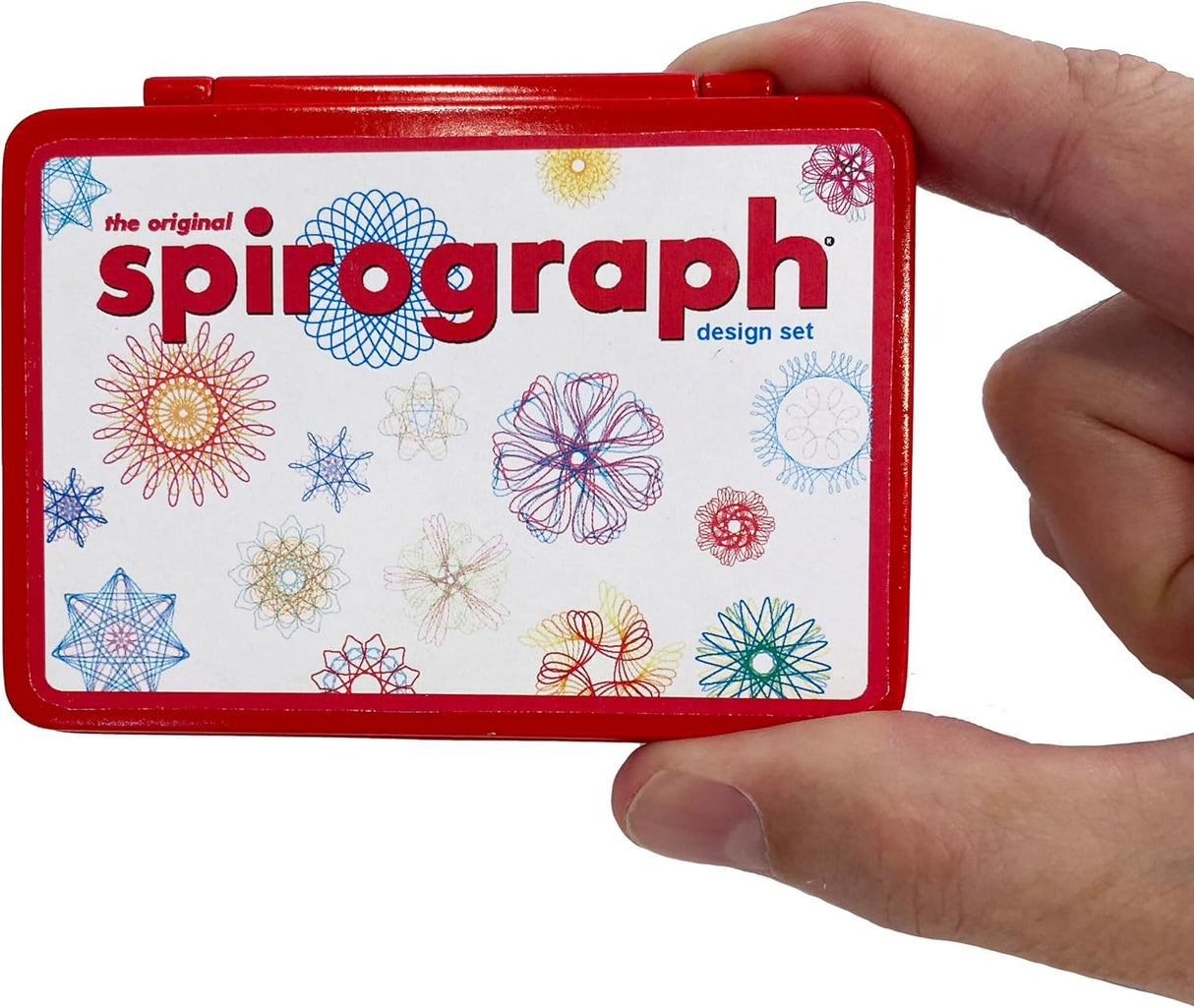 Hand holding the red compact case of the Worlds Smallest Spirograph with colorful designs on the label