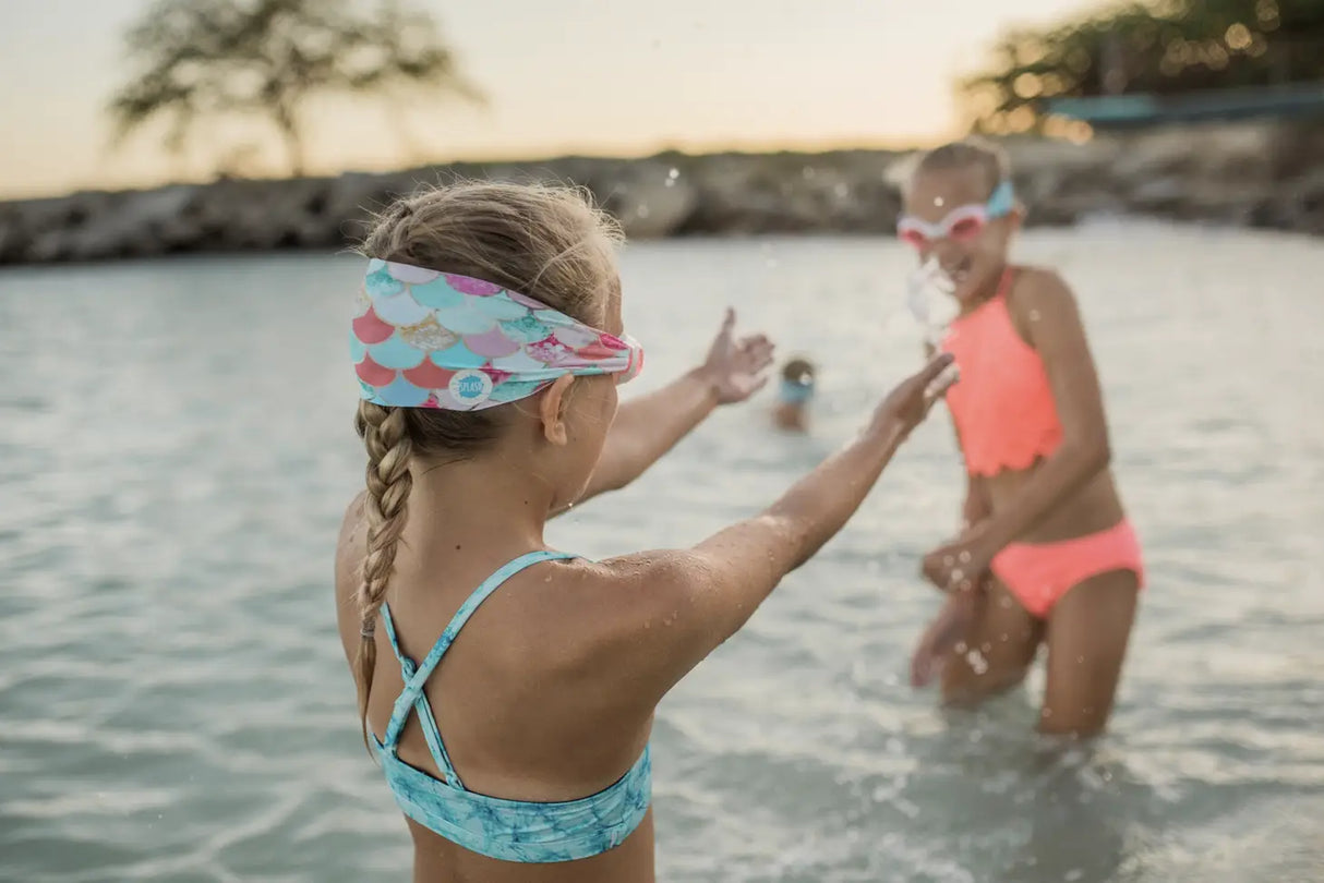 Two children playing in water wearing Goggles Mermaid with colorful mermaid scale straps and tinted lenses.